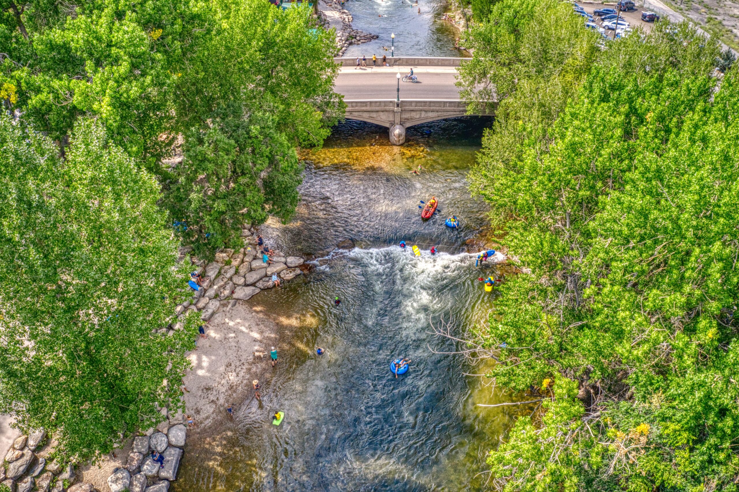 Overhead view of River with people floating and rafting with green trees around river
