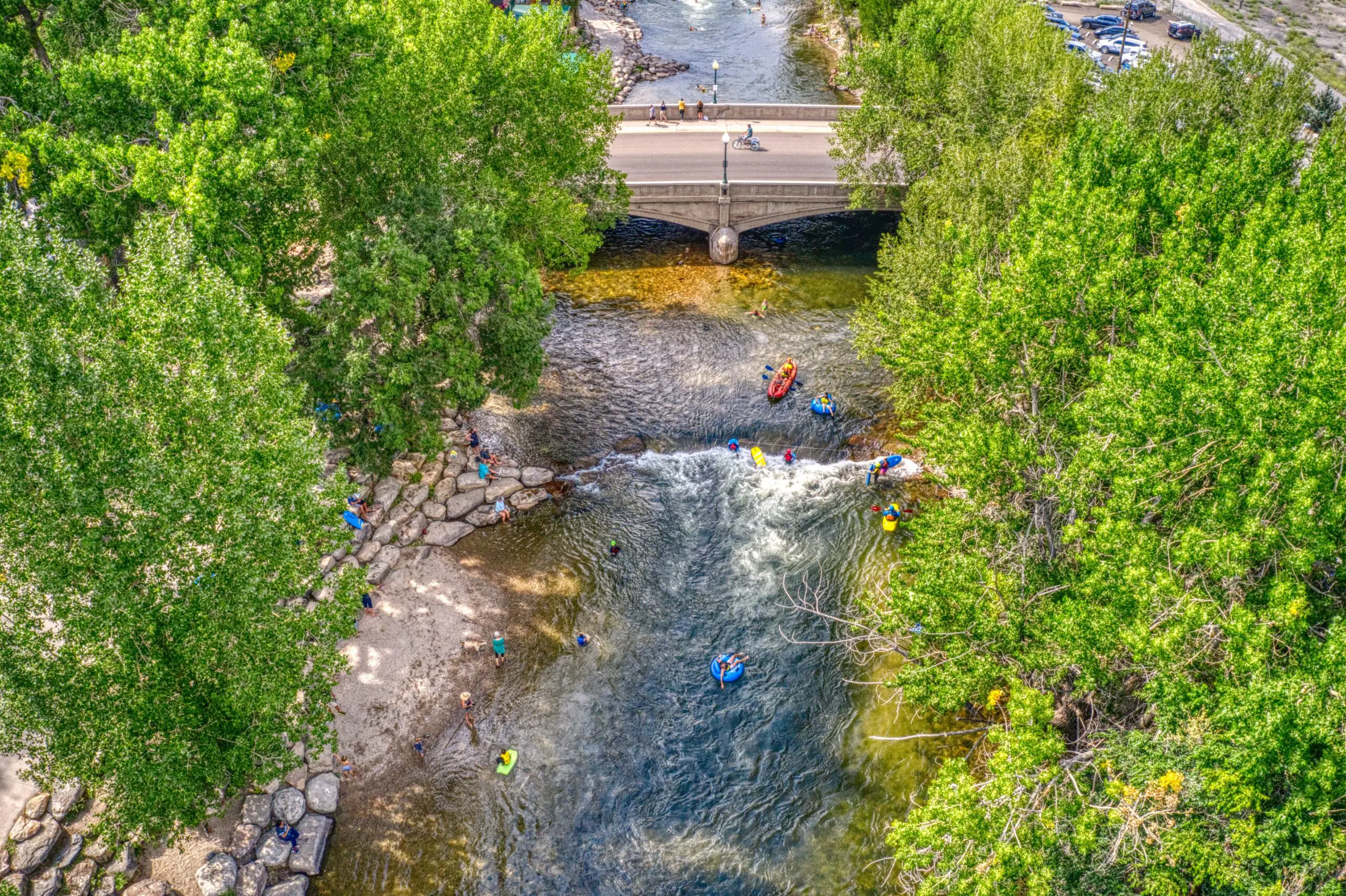 Overhead view of River with people floating and rafting with green trees around river